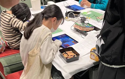 テーブルでタブレットを使ってアプリを体験する子ども